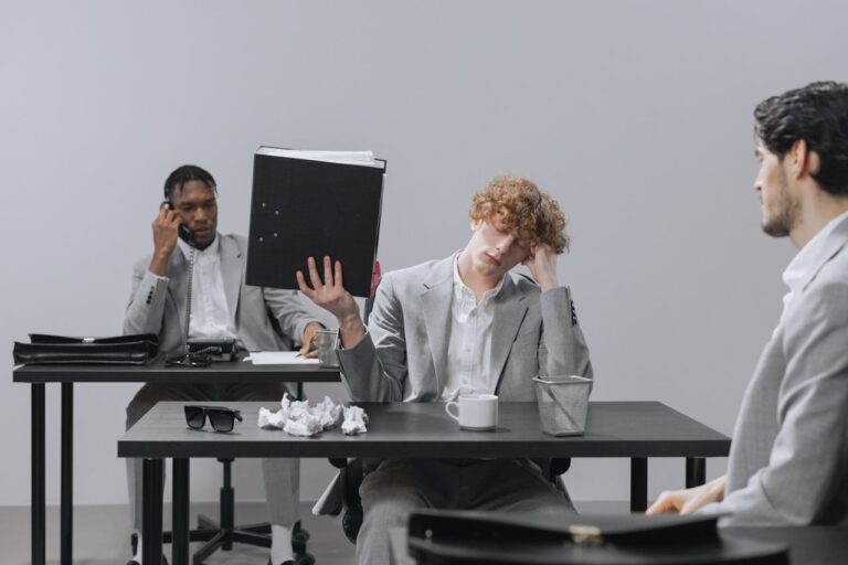 three men in gray suits sitting bored in an office
