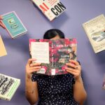 woman reading book with other books being handed to her