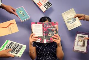 woman reading book with other books being handed to her