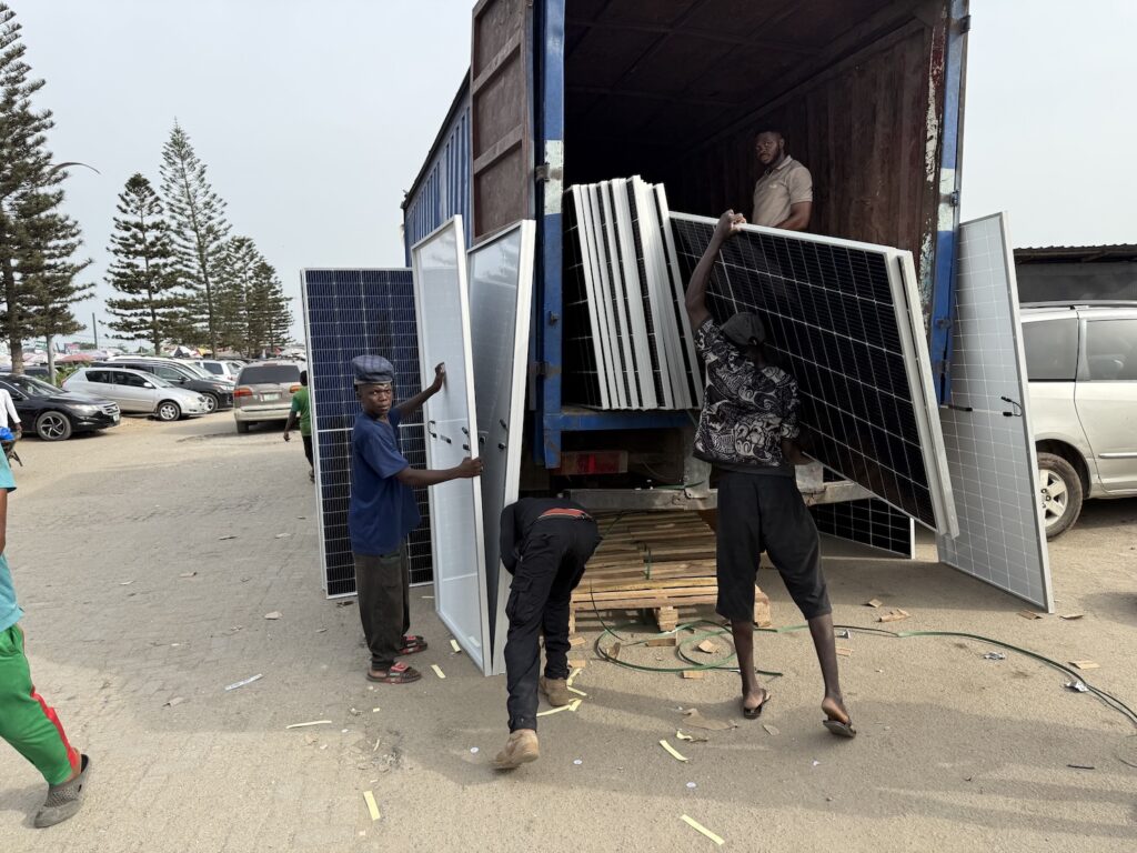 Workers offload solar panels from truck