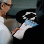 Business professionals conducting an interview with resume on clipboard in an office setting.