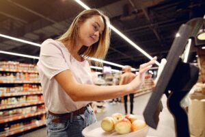 Woman uses self-checkout to buy apples at grocery store