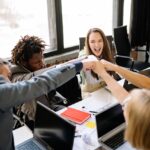 A diverse group of professionals celebrate a successful meeting with a fist bump.