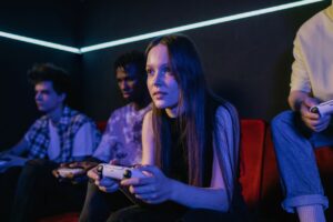 A diverse group of friends intensely playing video games with controllers on a sofa.