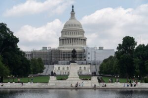 US Capitol with dome, statue, and reflecting pool on a sunny day in Washington, D.C.