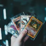 A hand holds collectible Charizard Pokemon cards with a blurred bokeh background. Perfect for trading card enthusiasts.
