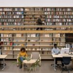 People reading and working in a public library full of books.