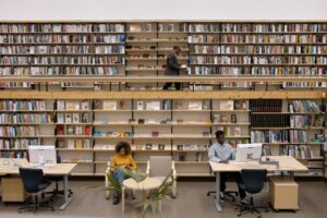 People reading and working in a public library full of books.