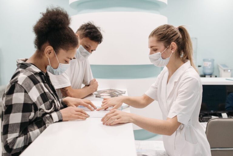 A healthcare professional in a medical setting assists patients at a clinic desk, emphasizing care and teamwork.